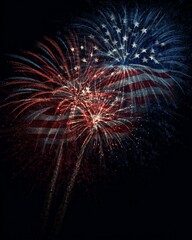 Bright fireworks in the night sky forming a display resembling the American flag with blue and red colors.
