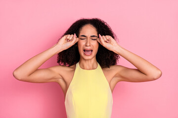 Young stylish woman in a yellow dress posing against a pink background with a humorous and...