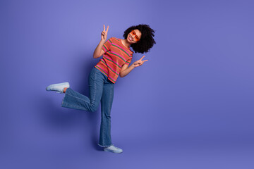 Cheerful young woman with vibrant style showing peace hand gestures on a colorful background