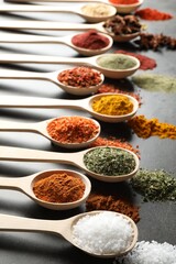Many different spices in spoons on grey table, closeup