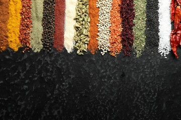 Many different spices on black table, flat lay. Space for text