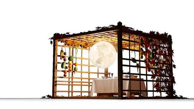 Decorated sukkah with hanging fruits and vegetables and a table set for a meal inside the structure