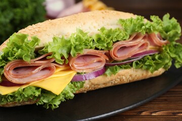 Tasty baguette sandwich with ham, cheese and vegetables on wooden table, closeup