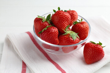 Fresh ripe strawberries in bowl on white wooden table, closeup