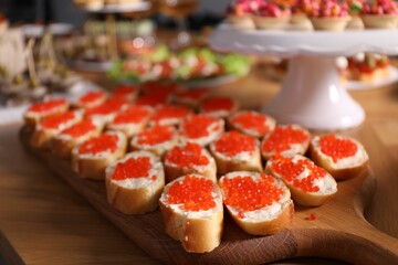 Buffet menu. Sandwiches with red caviar on wooden table, closeup