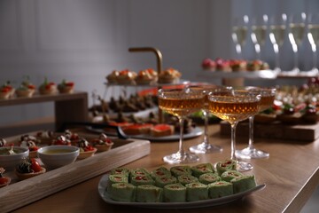 Buffet menu. Glasses of sparkling wine and tasty appetizers on table, closeup