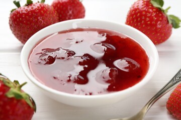 Tasty strawberry jam in bowl and fresh berries on white wooden table, closeup