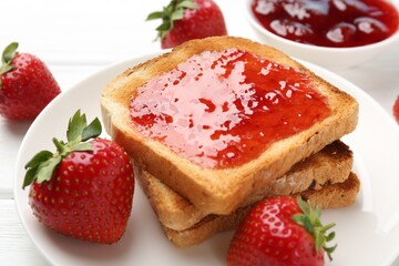 Toasts with tasty strawberry jam and fresh berries on white table, closeup