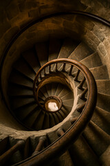 Fototapeta premium Spiral staircase in stone with wooden railing perspective from above