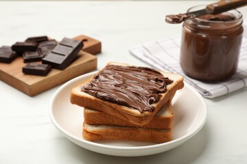 Tasty chocolate butter and slices of bread on white table, closeup