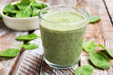 Tasty smoothie and spinach leaves on wooden table, closeup