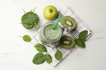 Tasty smoothie in mason jar, spinach leaves, kiwi and apple on white marble table, flat lay