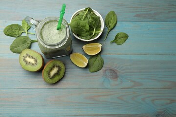 Tasty smoothie in mason jar, spinach leaves, kiwi and lime on light blue wooden table, flat lay....