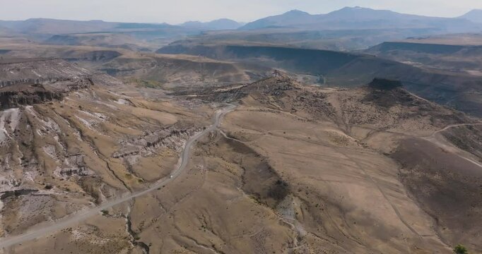 Aerial view shows a winding road through a dry and hilly landscape. North of Neuquen province, Argentina