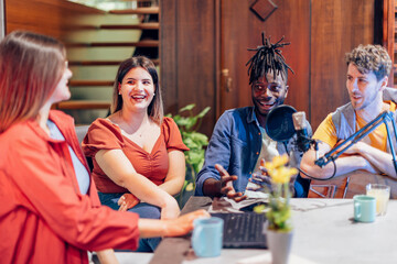Content creators recording podcast in home studio with diverse team