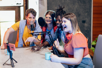 Group of friends creating online podcast using microphone and smartphone in home studio