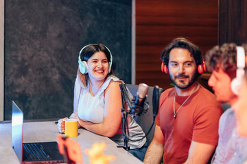 Radio hosts recording podcast in studio, using professional microphone and headphones