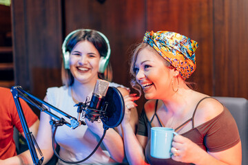 Two smiling women recording a podcast in a professional studio