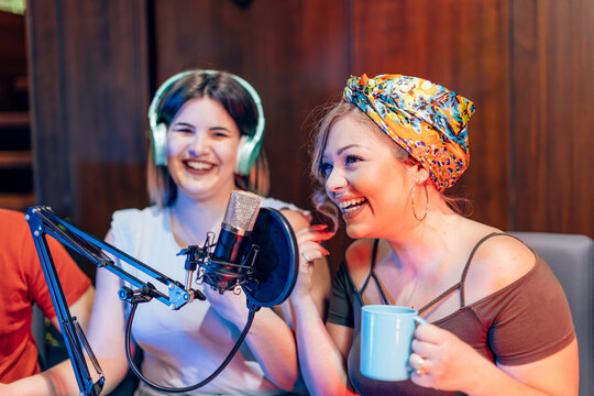 Two smiling women recording a podcast in a professional studio - Powered by Adobe