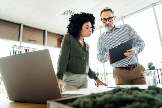 Professional coworkers collaborating on a business project while analyzing report data together in a modern office workspace