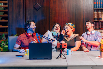 Podcasters laughing while recording a podcast in home studio