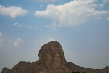Hasat Al-Salt, a natural rock formation in Al Hamra, Oman, stands tall beneath a blue sky.

