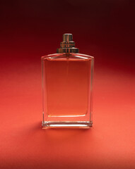 A transparent bottle of perfume, cologne or eau de toilette on a red background. Fragrance...