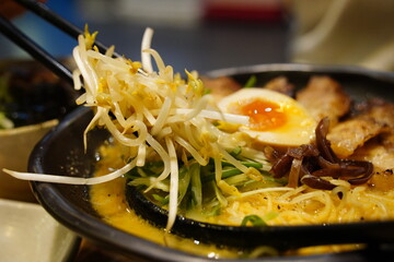 Close-up of Japanese Ramen Noodles with Chashu Pork, Soft-Boiled Egg, and Bean Sprouts in a Black Bowl