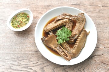 chop boiled duck wing and beak with tongue stew in brown soy soup on plate dipping spicy sour chili sauce 