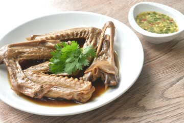 chop boiled duck wing and beak with tongue stew in brown soy soup on plate dipping spicy sour chili sauce 