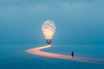 Person walking on glowing path toward cloud-shaped light bulb in surreal foggy landscape, symbolizing creativity and discovery. Copy space