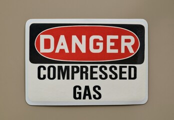 Danger Compressed Gas safety sign warning notice on wall industrial occupation.
