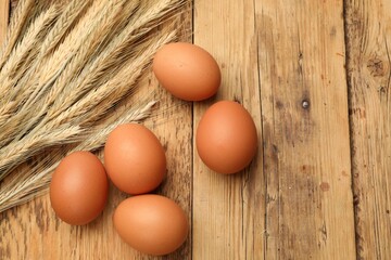 Fresh eggs and spikes on wooden table, flat lay. Space for text