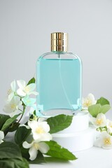 Bottle of perfume and jasmine flowers on light background, closeup