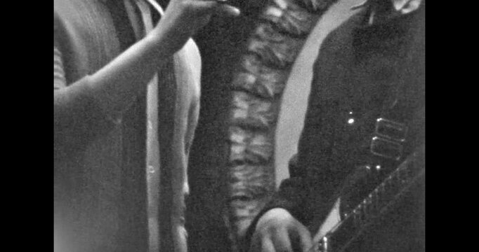 An artist plays the guitar on stage. Hands pluck the strings of the guitar. Ensemble performance. Archival video, 1970s, USSR.