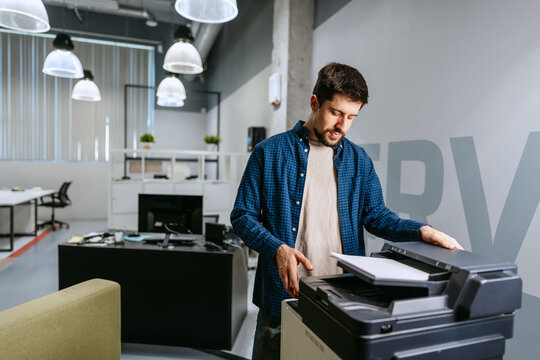 Man operating a printer in a modern office environment during working hours