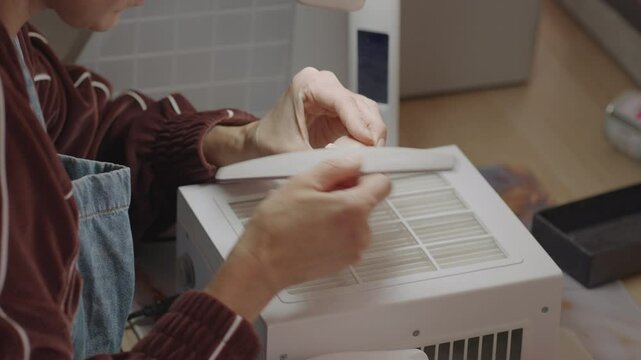 Artist smoothing silicone doll face with sanding tool near vented surface, showing precision work in clean, well-lit workspace focused on fine detailing