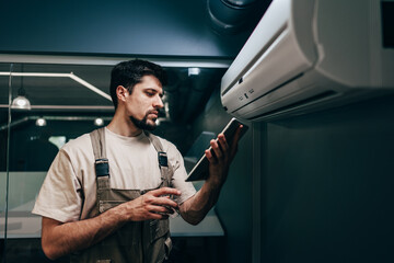Technician performs maintenance on air conditioning unit while checking data on tablet