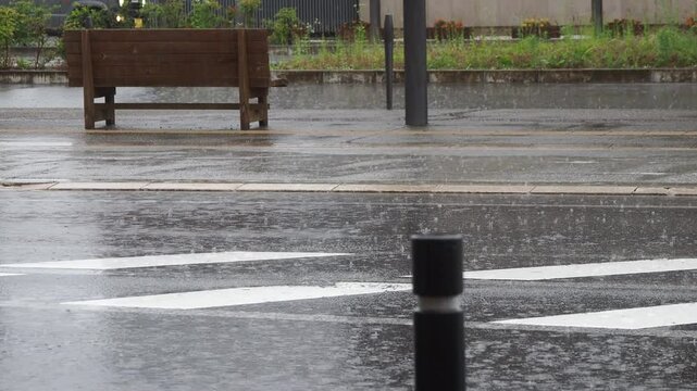 猛烈な雨と街の道路とバス停の様子