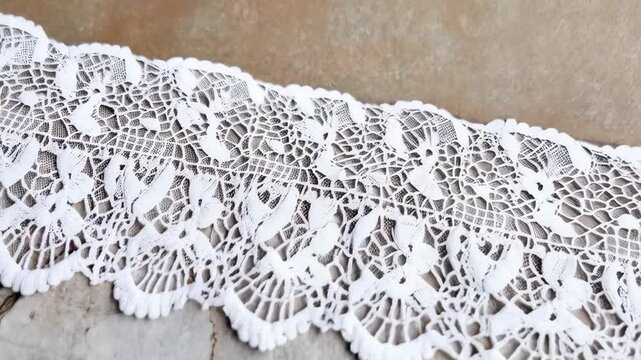 Intricate white lace trim resting on cracked marble background, textile craftsmanship, decorative border, elegant fabric detail, surface backdrop