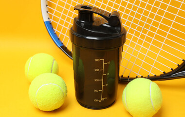 Tennis racket, sports bottle and ball on yellow background