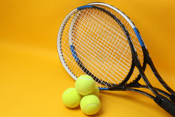 Tennis racket, sports bottle and ball on yellow background
