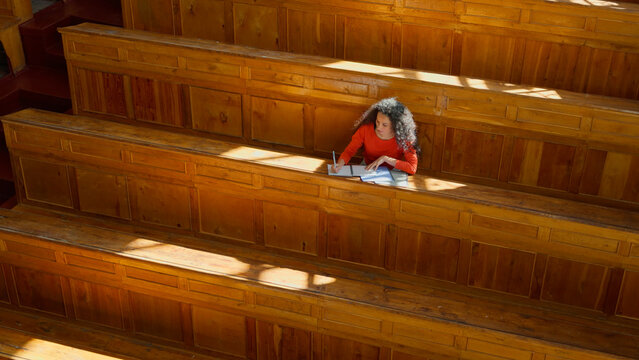 Distant view Caucasian girl student Hispanic woman Latina American female in university college auditorium high school academy writing task homework test exam write in classroom study education learn