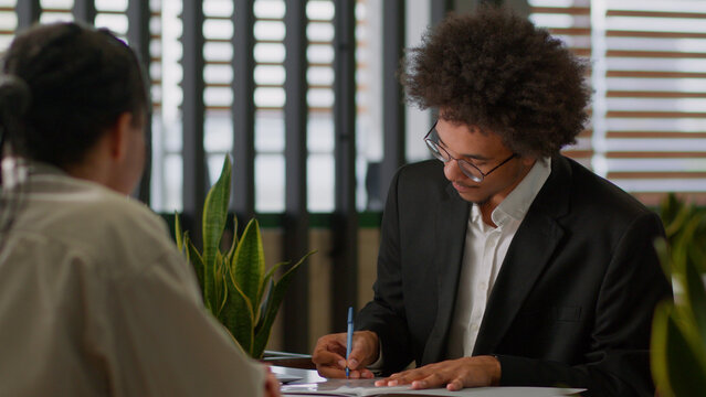 Two business men colleagues signing contract agreement happy deal cooperation partnership African American businessmen in office ethnic man guy male sign paper document bank insurance - Powered by Adobe