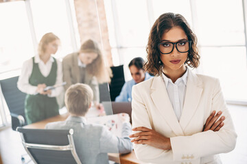 Obraz premium Confident businesswoman in white formalwear leading a team meeting in a modern office workspace with colleagues