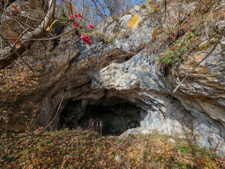 Wide cave entrance framed by autumn foliage on the Bükk Plateau. The Három-kúti Cave is known for its geological features and prehistoric finds.