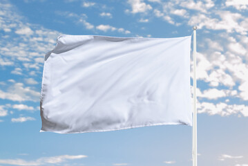 White flag stretches with movement in open sky, ideal for peaceful concepts, surrender symbolism,...