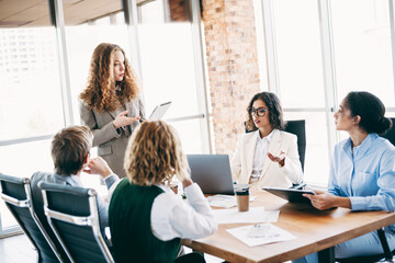 Group of professionals collaborating during an office meeting discussing project strategies in a...