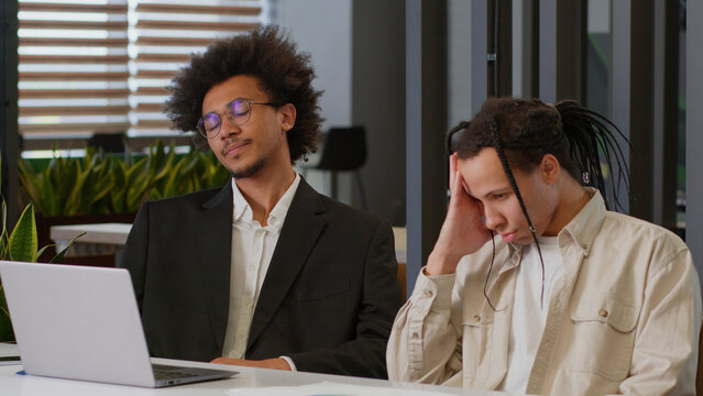 Two African American men business guys colleagues desperate stressed worried businessmen coworkers working together internet laptop at office online failure sad bad news computer problem notification