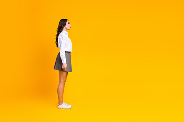 Stylish woman in trendy outfit standing against bright yellow background showcasing fashion and confident business persona